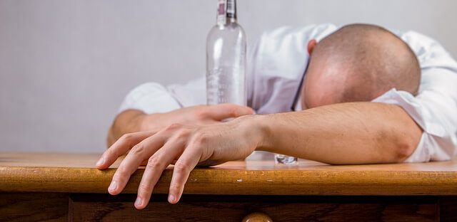 alkoholik na kacu z pustą butelką w ręce