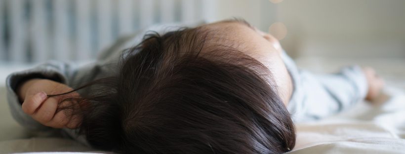 Śpiące niemowlę leżące na łóżeczku w delikatnym świetle