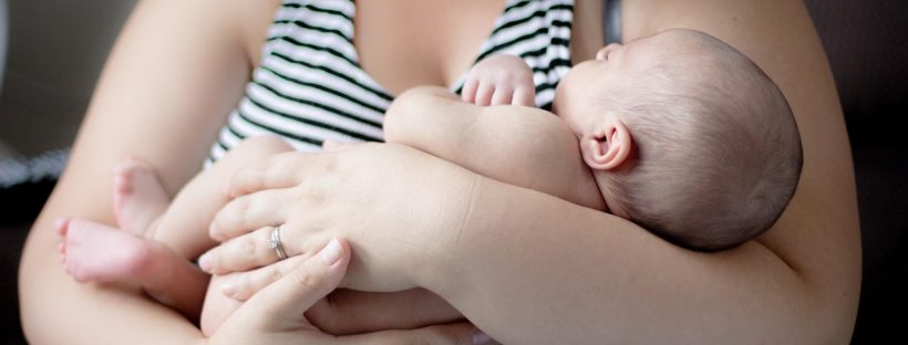 Młoda mama trzyma i tuli noworodka