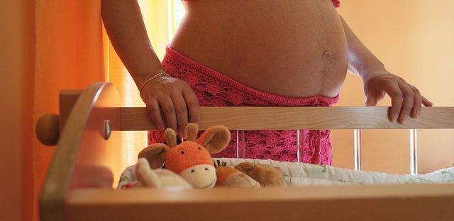 kobieta w ciąży przy dziecięcym łóżeczku